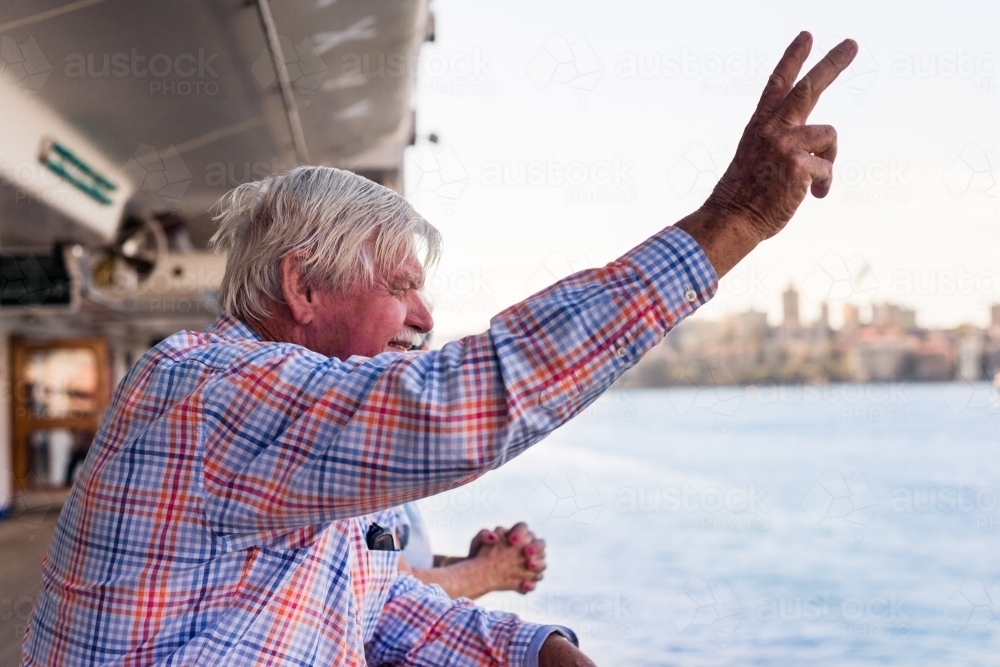 happy senior man waves as cruise departs - Australian Stock Image