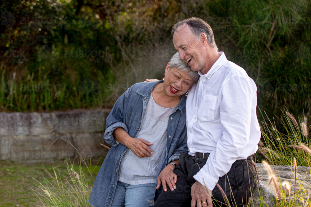 Happy senior woman resting her head on mans chest at the harbour laughing - Australian Stock Image