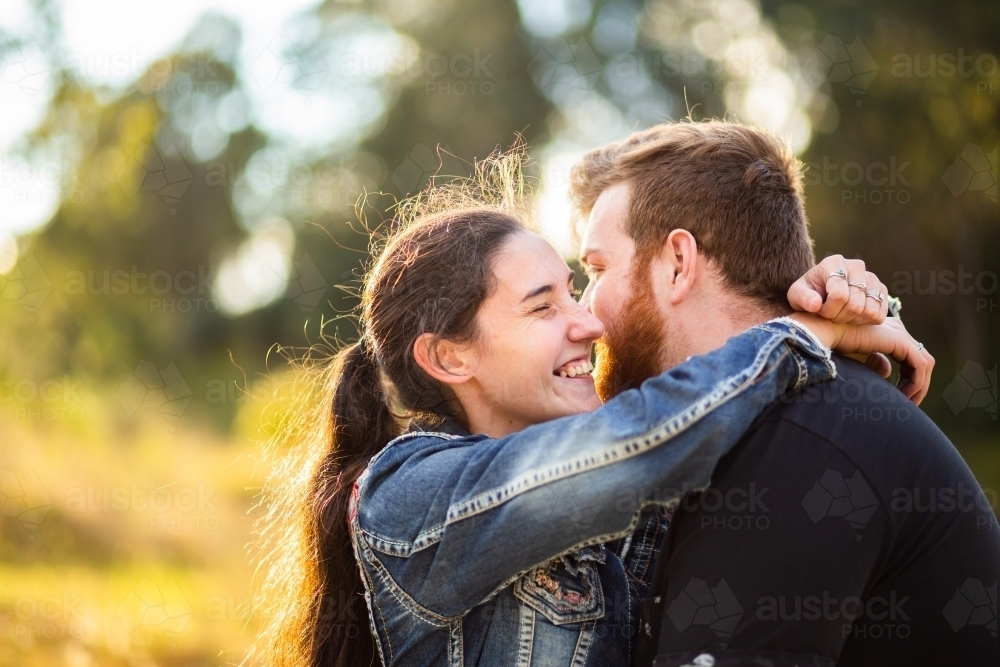 Happy smiling aussie couple in their twenties hug one another - Australian Stock Image