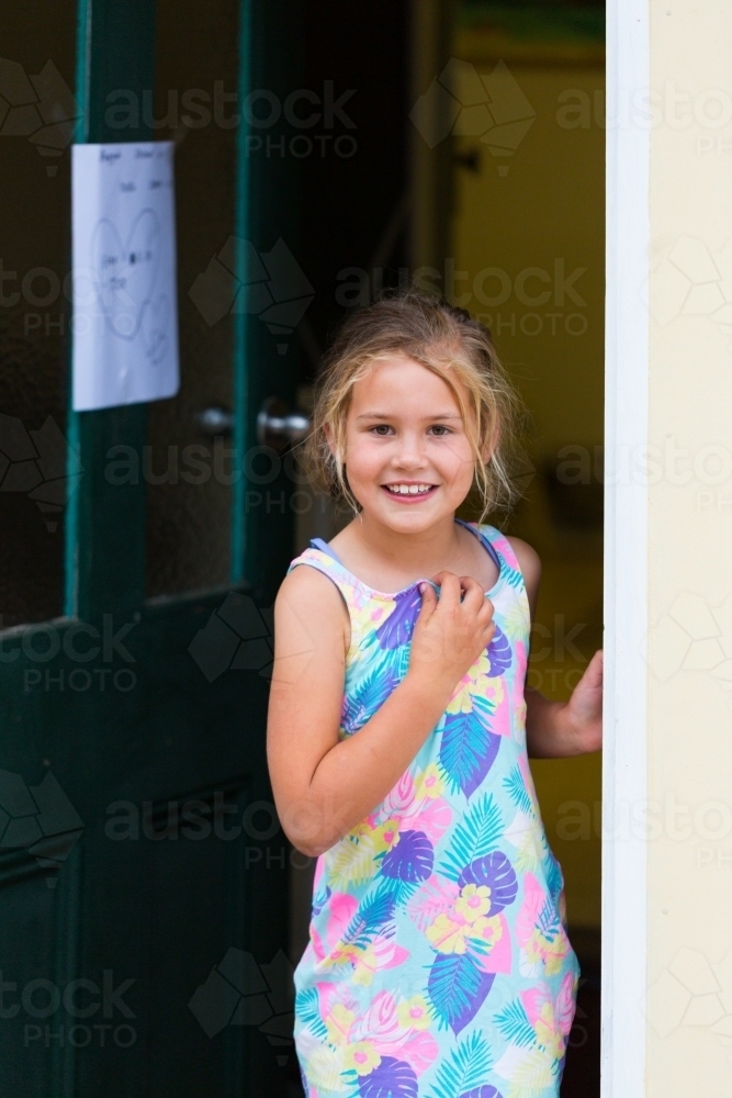 Happy smiling child looking out of doorway - Australian Stock Image
