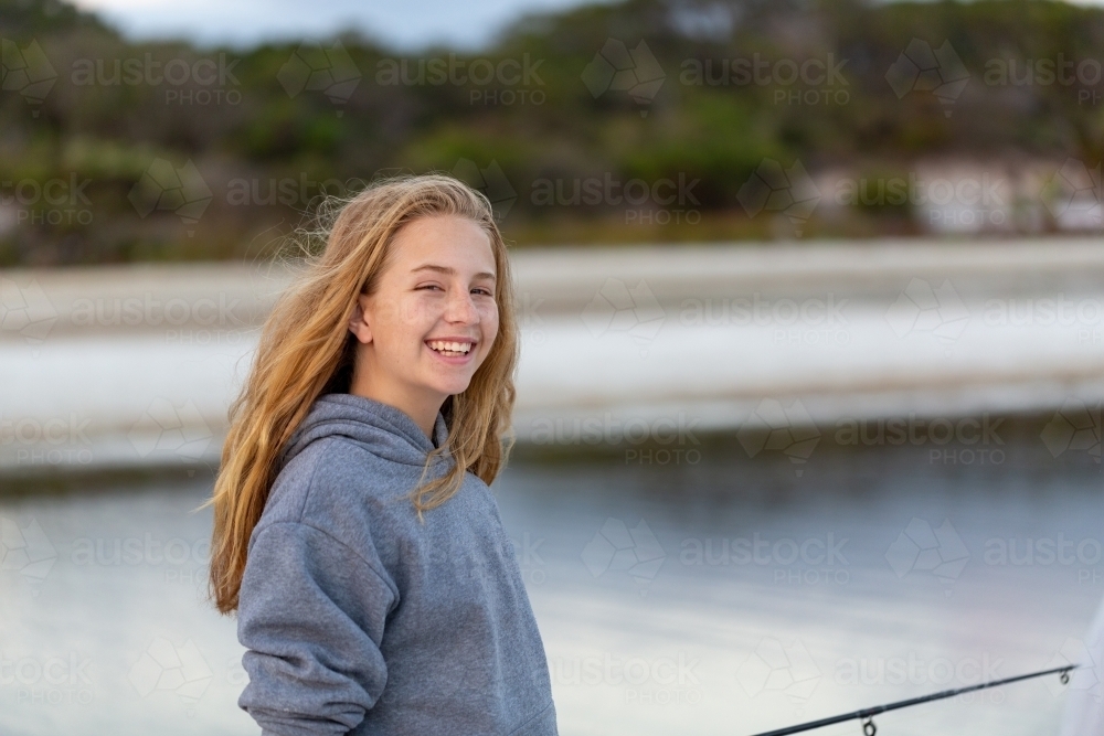 Happy smiling long-haired girl outdoors near water - Australian Stock Image