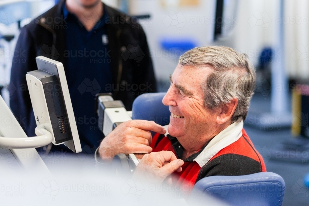 happy smiling male physio client with physiotherapist using exercise therapy equipment - Australian Stock Image