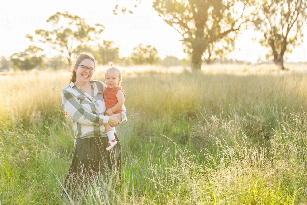 Happy smiling portrait of mother and daughter together in farm paddock - Australian Stock Image