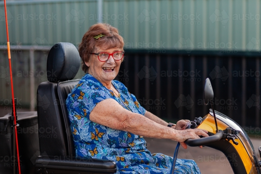 Happy smiling senior person on mobility scooter - Australian Stock Image