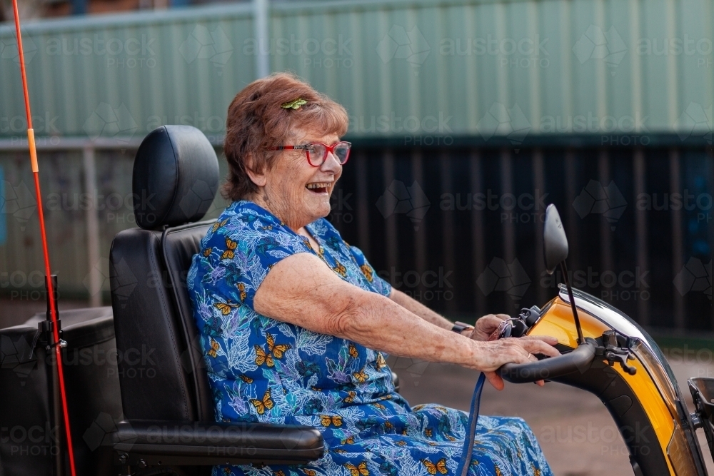 Happy smiling senior person on mobility scooter - Australian Stock Image