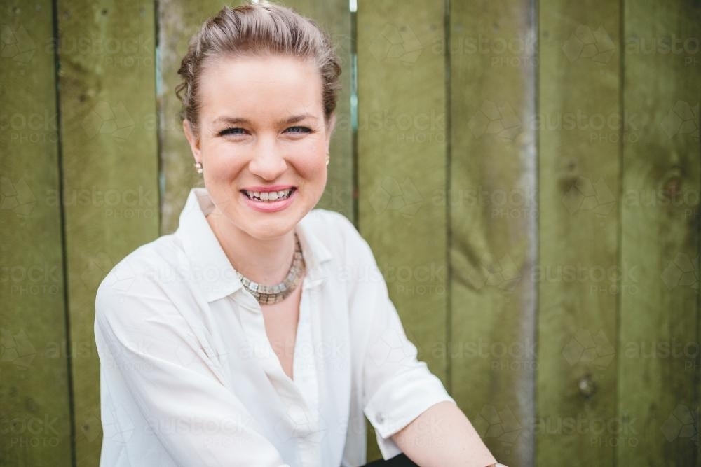 Happy smiling woman against fence - Australian Stock Image