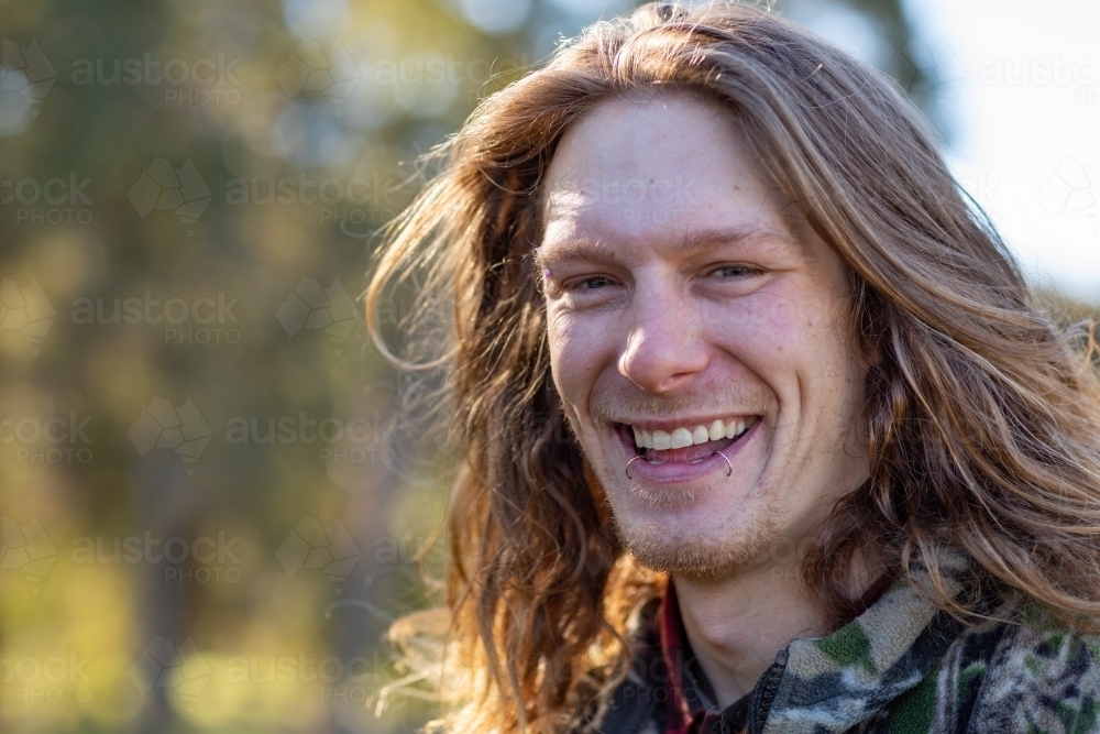 happy smiling young man head and shoulders outdoors - Australian Stock Image