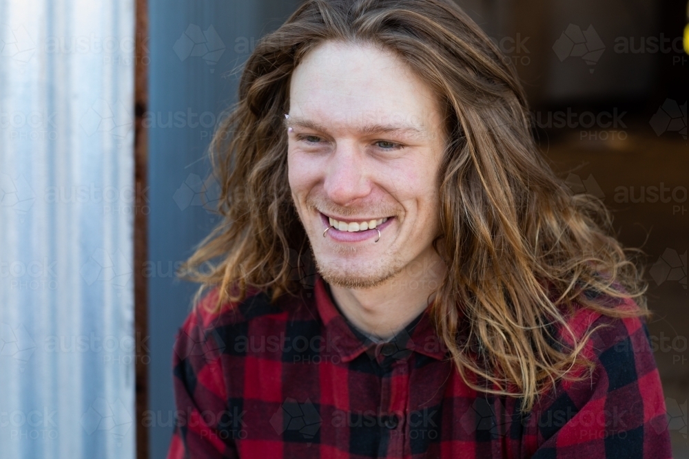 Happy smiling young man with long hair and lip piercings - Australian Stock Image