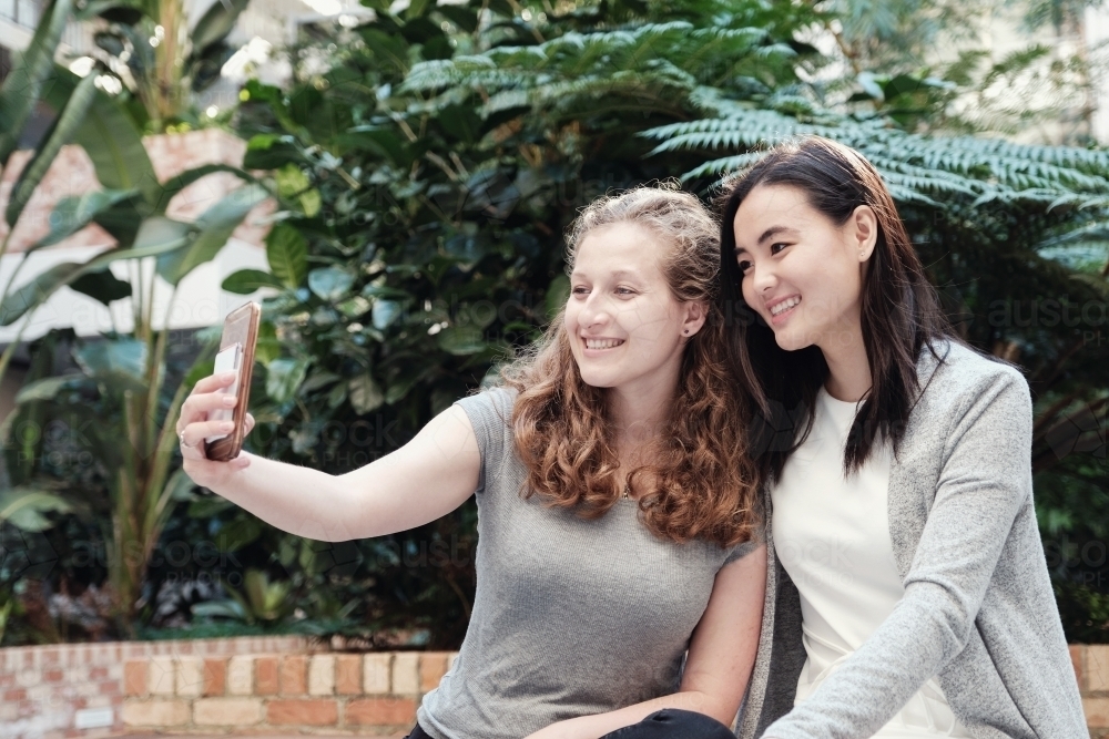 Happy students girl friends using mobile : Austockphoto Happy students girl friends using mobile - Australian Stock Image