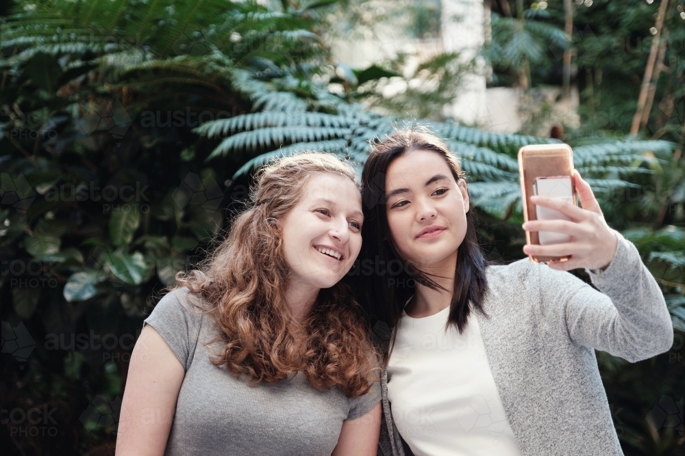 Happy students girl friends using mobile : Austockphoto Happy students girl friends using mobile - Australian Stock Image