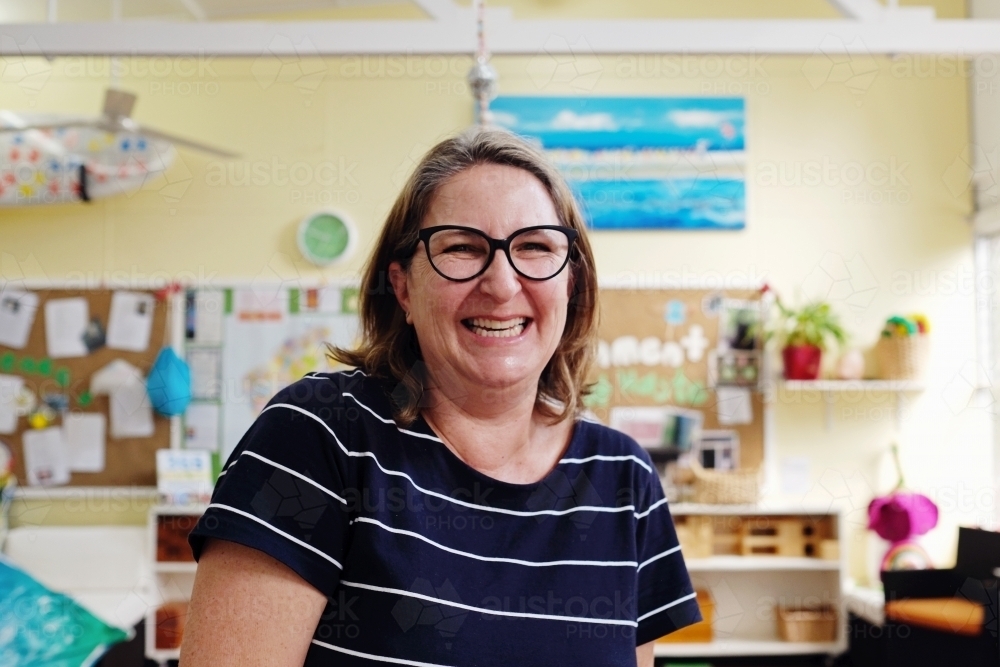 Happy teacher in kindergarten classroom, childcare, preschool educator - Australian Stock Image
