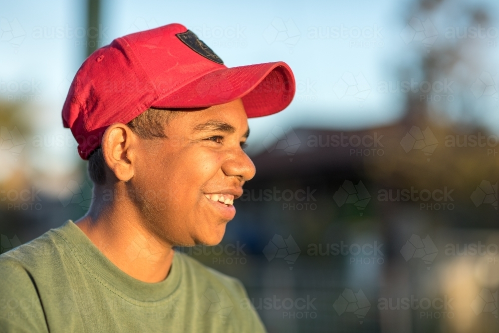 happy teen boy wearing red cap with blurry background - Australian Stock Image