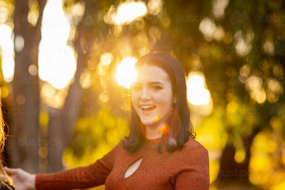 happy teen girl backlit with golden light and sun flare - Australian Stock Image
