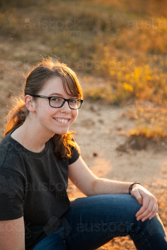 Image of Happy teen girl sitting outside in the paddock - Austockphoto