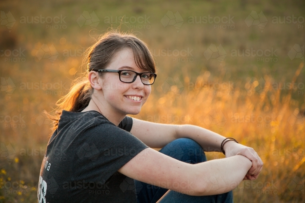 Image of Happy teen girl sitting outside in the paddock - Austockphoto