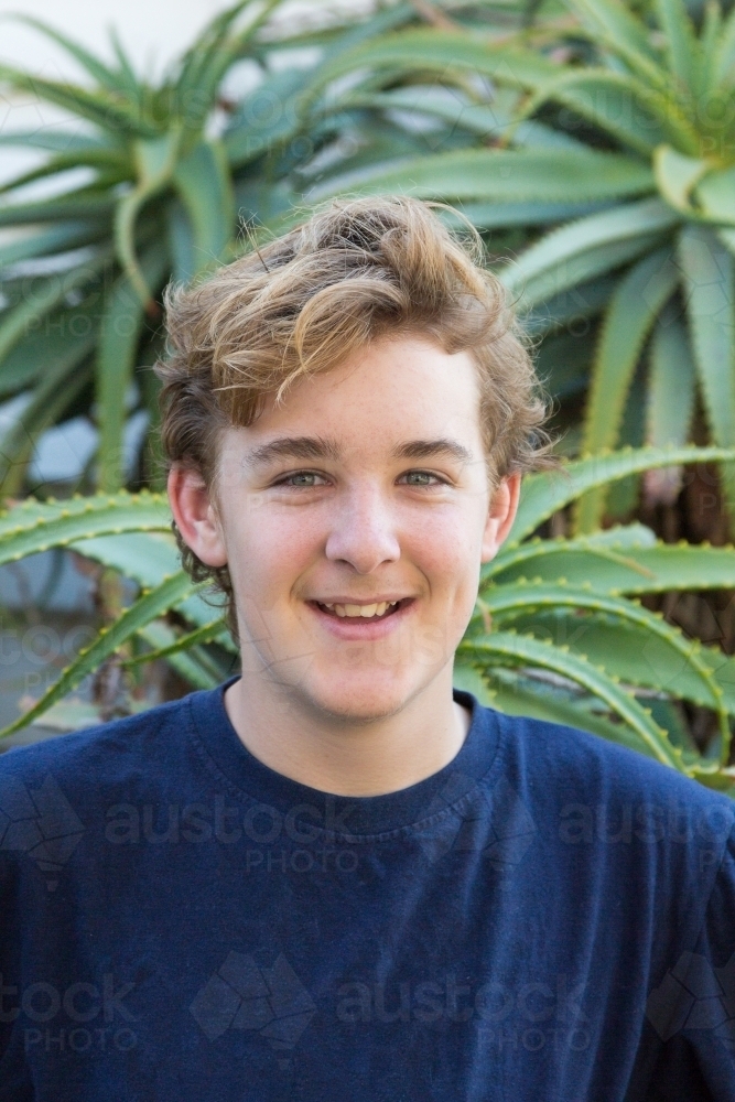 Happy teenage boy in front of cactus plant - Australian Stock Image