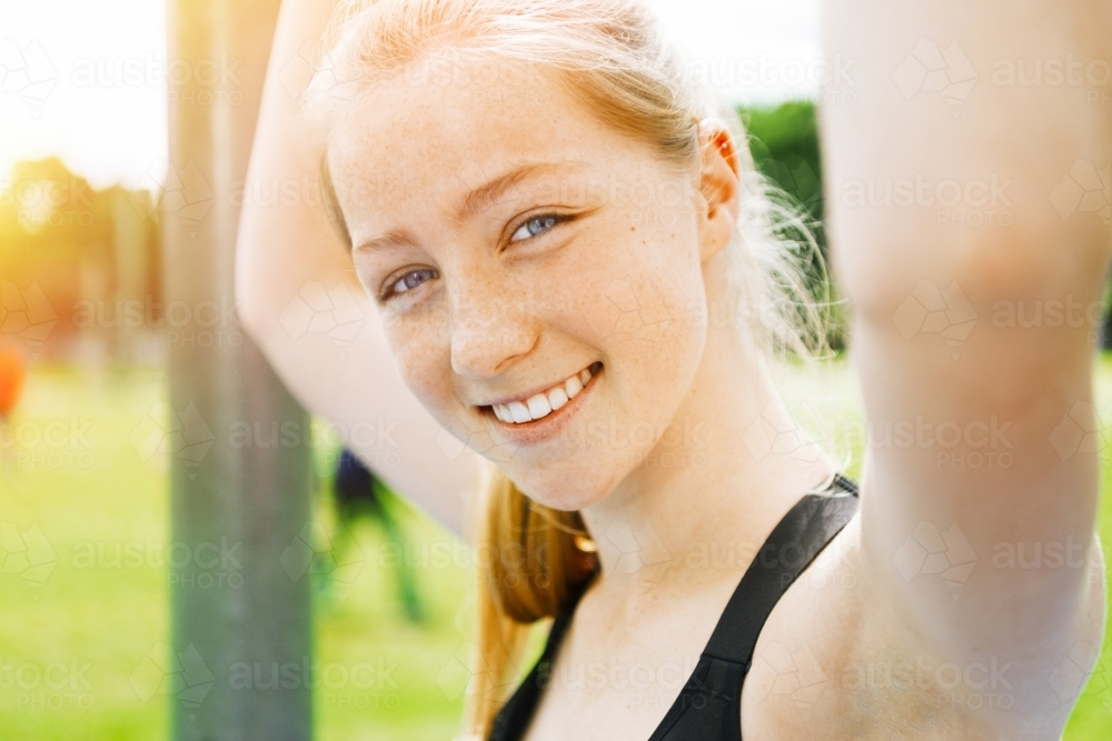 Happy teenage girl smiling while holding up her arms - Australian Stock Image