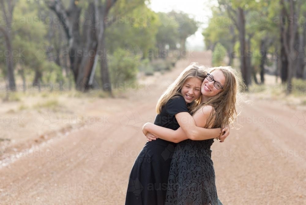 Happy teenage girls hugging in country landscape - Australian Stock Image