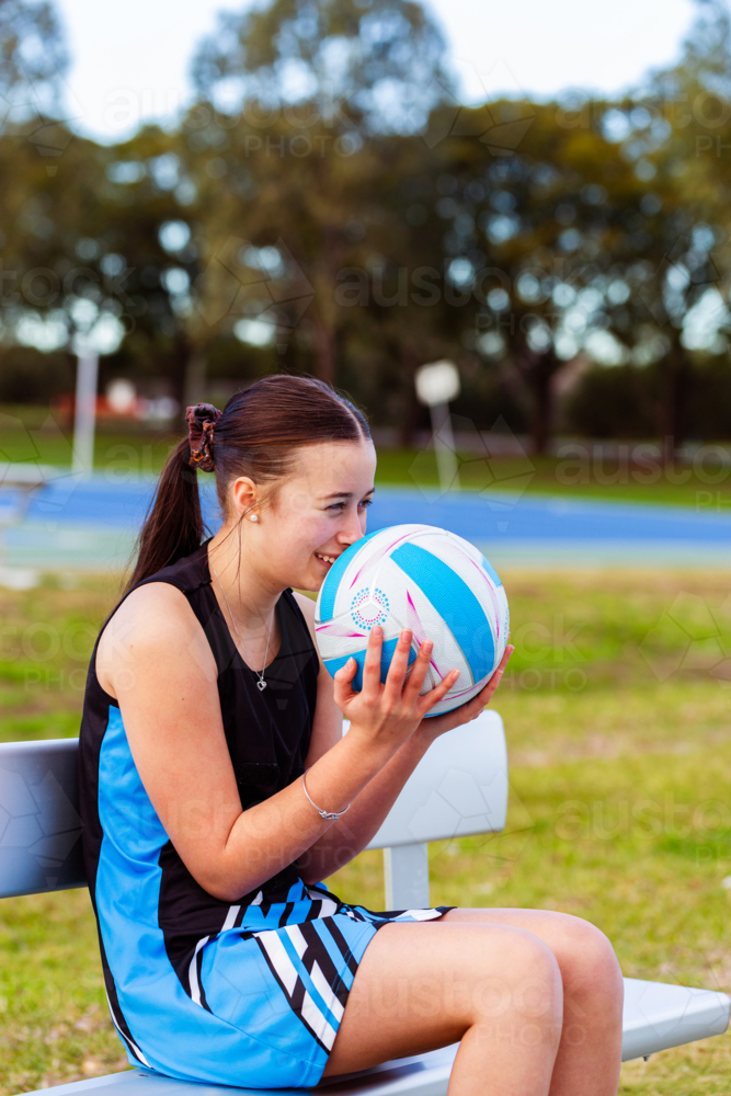 Happy teenaged aboriginal netball player laughing with ball - Australian Stock Image