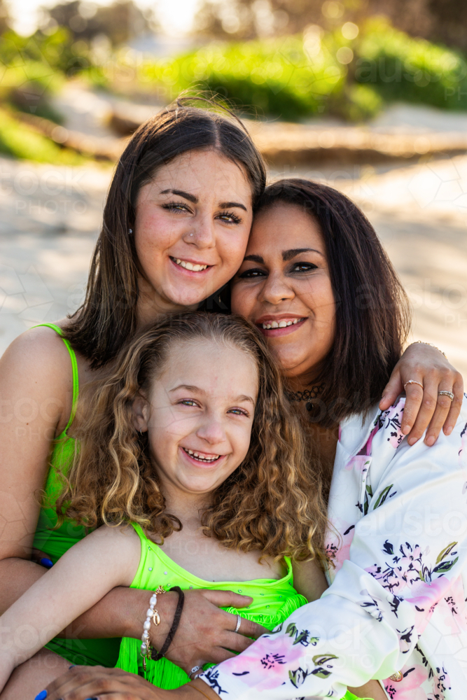 happy Torres Strait Islander family with mum and two daughters together at beach - Australian Stock Image