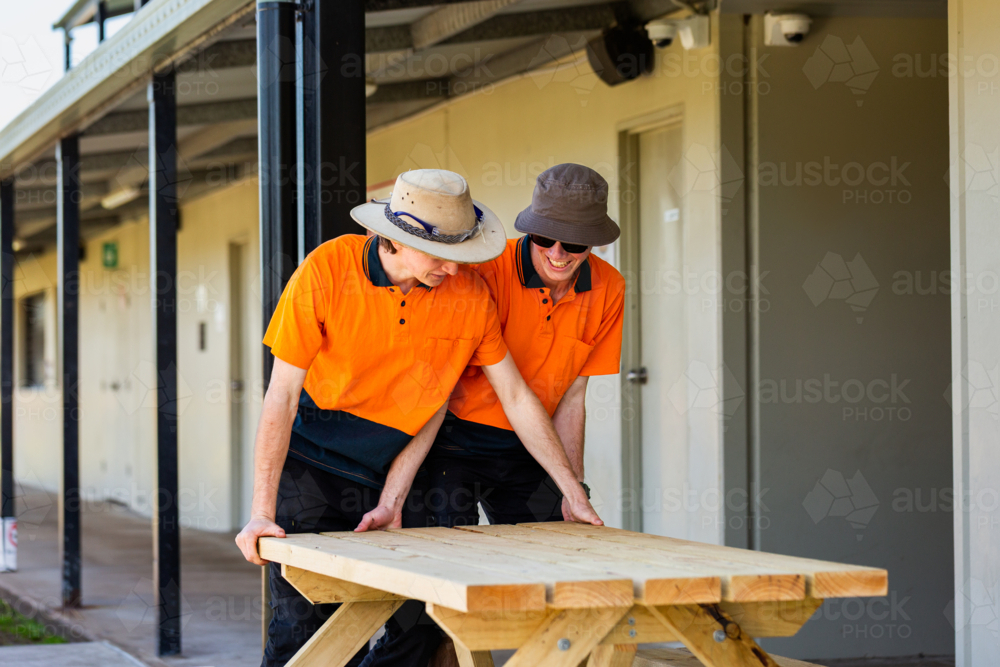 Image of Happy trade apprentices moving table they built during hands ...