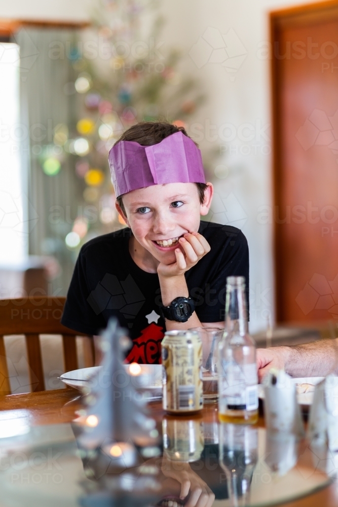 Happy tween boy at Christmas time wearing a paper crown hat - Australian Stock Image