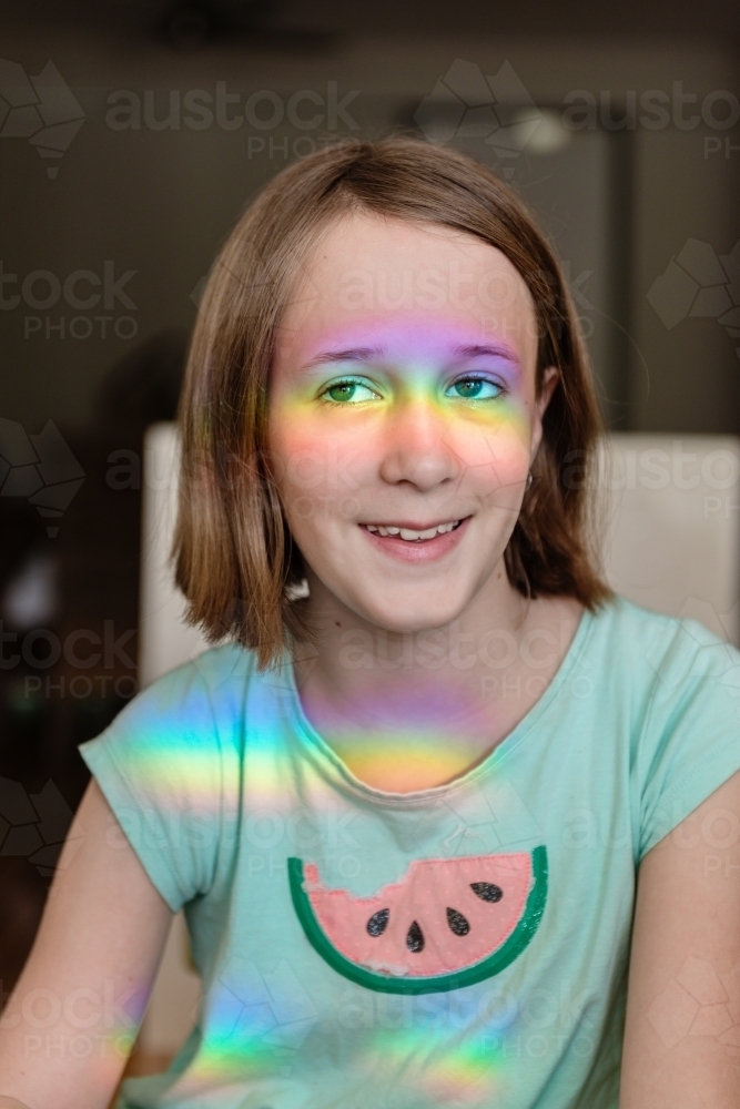 Image of Happy tween girl with rainbow shadow on her face - Austockphoto