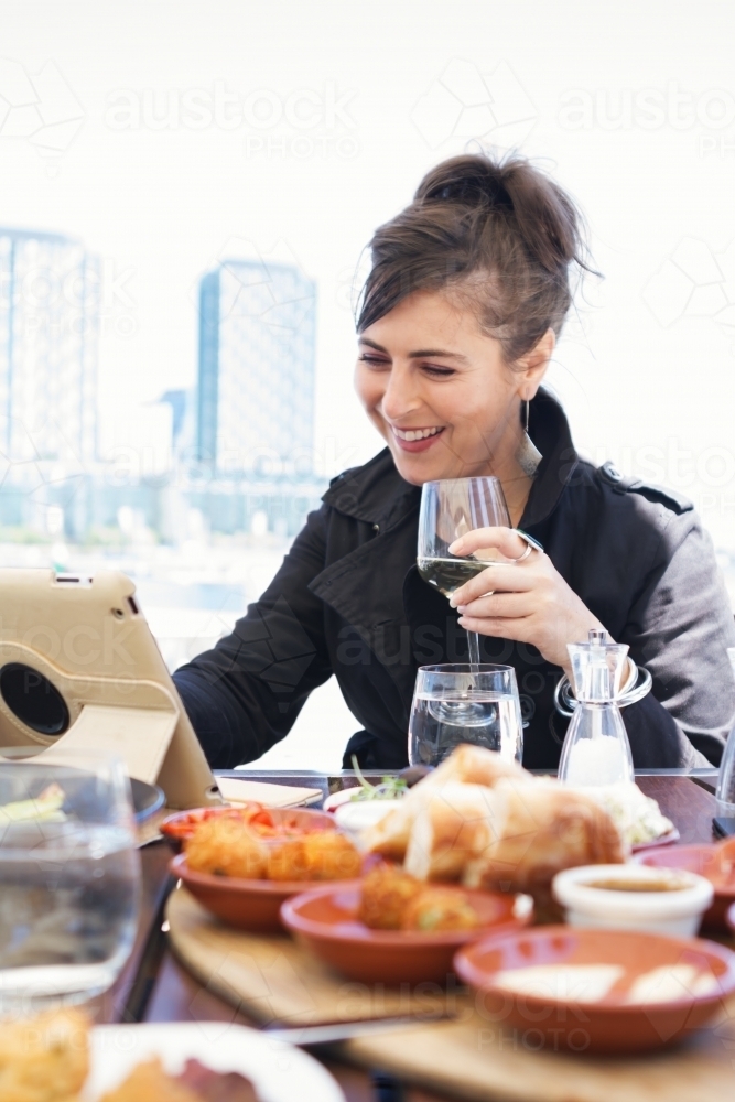 Happy woman browsing the internet at a solo lunch - Australian Stock Image