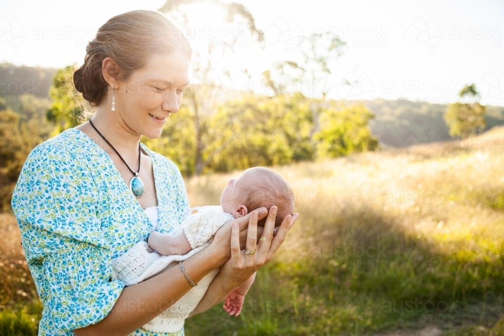Happy woman holding her newborn daughter outside - Australian Stock Image