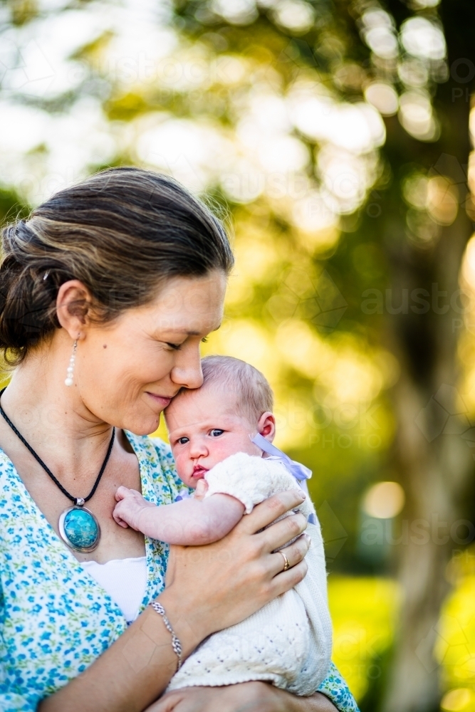 Happy woman holding her newborn daughter outside - Australian Stock Image
