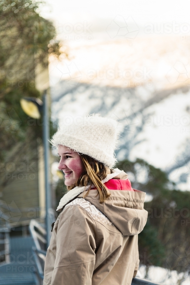 happy woman in ski resort, she is wearing a parka and beanie - Australian Stock Image
