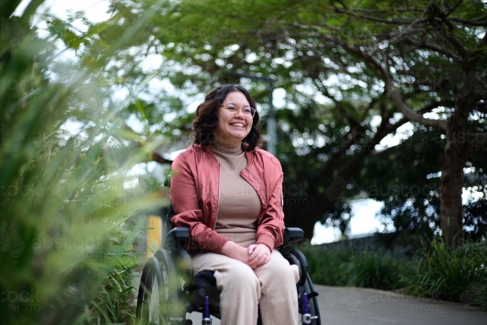 Happy woman in wheelchair in park - Australian Stock Image