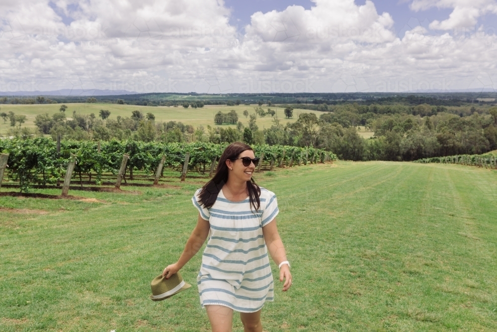Happy woman walking through the vineyard on a summer day - Australian Stock Image