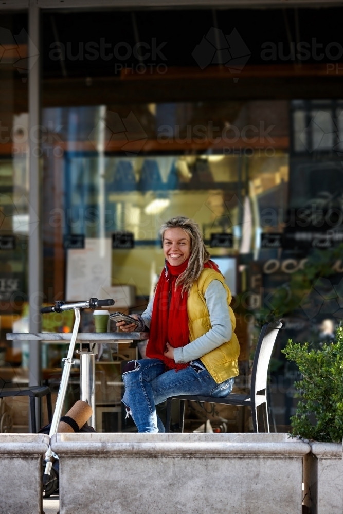 Happy woman with dreadlocks at cafe with electric scooter - Australian Stock Image