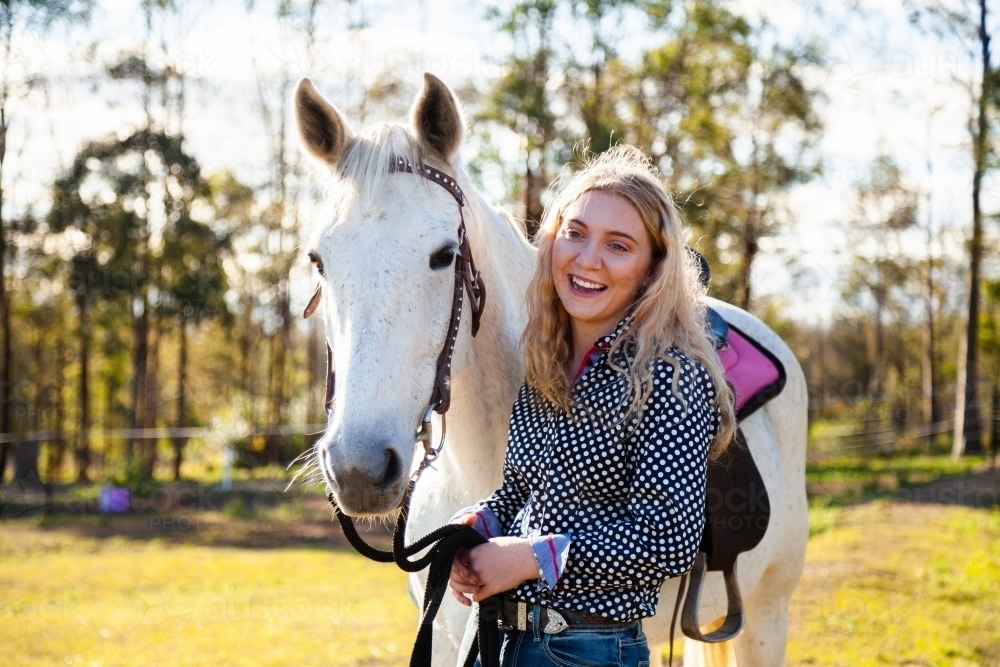 Happy young adult person laughing with her horse in Aussie sunlight - Australian Stock Image