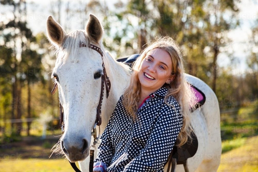 Happy young adult person laughing with her horse in Aussie sunlight - Australian Stock Image