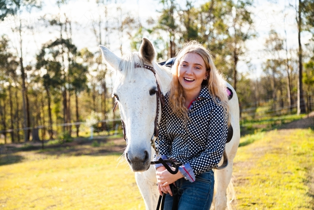 Happy young adult person laughing with her horse in Aussie sunlight - Australian Stock Image