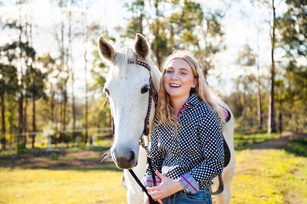 Happy young adult person laughing with her horse in Aussie sunlight - Australian Stock Image