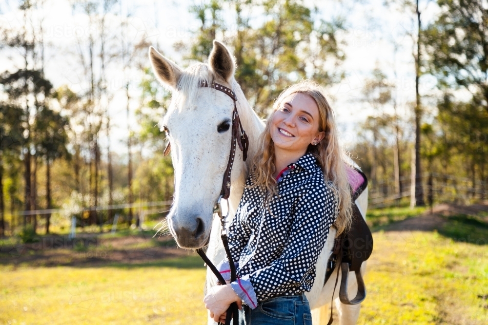 Happy young adult person laughing with her horse in Aussie sunlight - Australian Stock Image