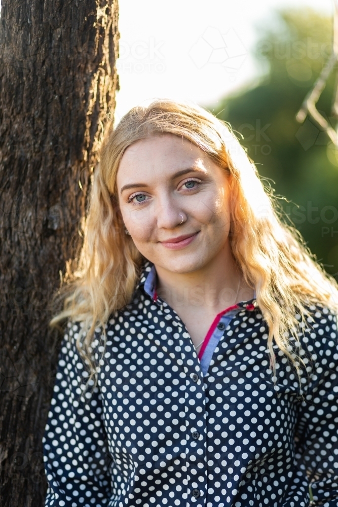 Image of Happy young adult person standing against a tree outside ...