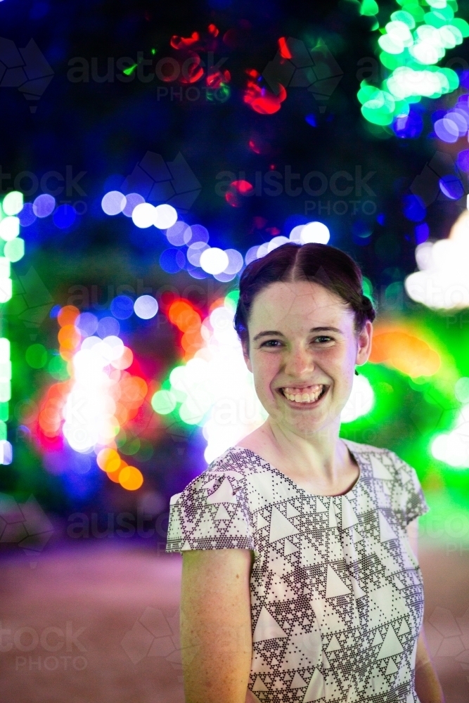 Happy young adult woman smiling during Christmas season with bokeh lights - Australian Stock Image