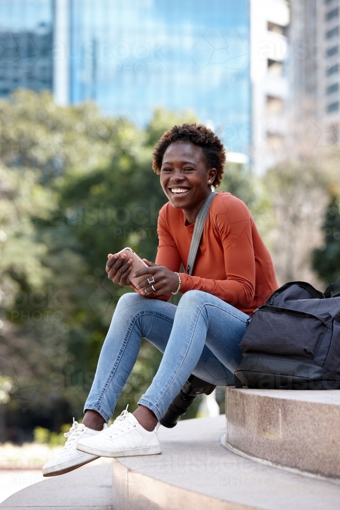 Happy young African woman photographer on steps - Australian Stock Image