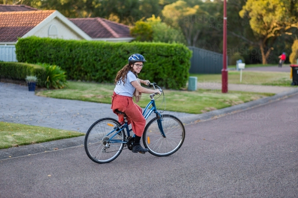 Happy young Australian woman on a bike riding down the road - Australian Stock Image