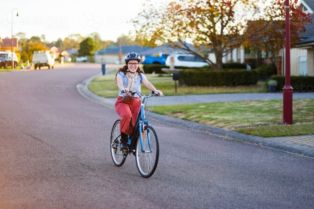 Happy young Australian woman on a bike riding down the road - Australian Stock Image