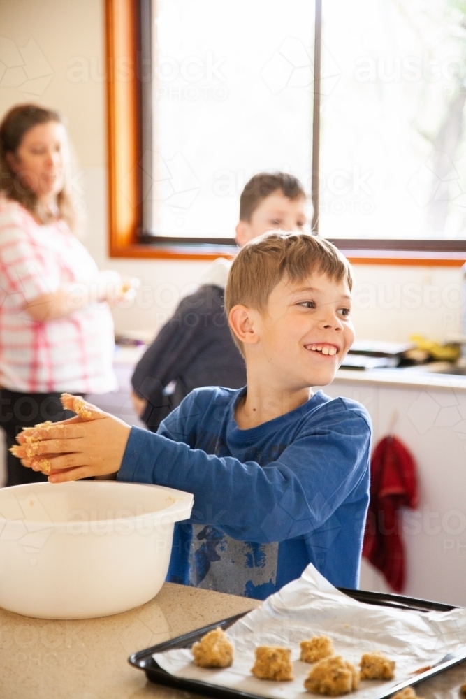 Happy young boy baking in the kitchen - Australian Stock Image