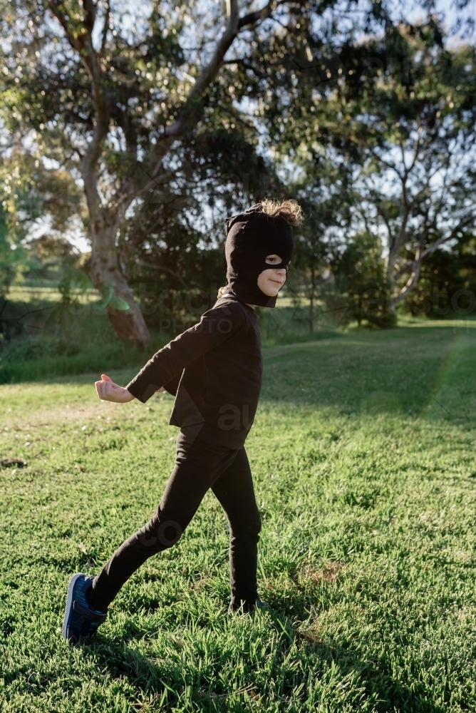 Happy young boy dressed up in a Ninja costume, wearing a mask made from mum's pantyhose (stockings) - Australian Stock Image