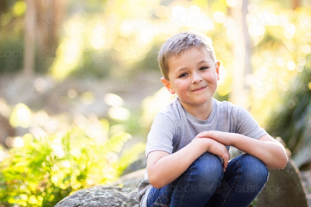 Happy young boy in park beside creek with copy space - Australian Stock Image