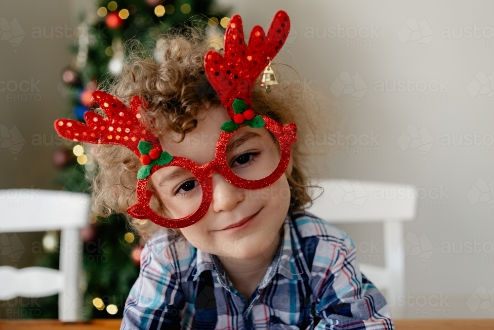 Happy, young boy wearing novelty glasses celebrating Christmas at home in Australia - Australian Stock Image