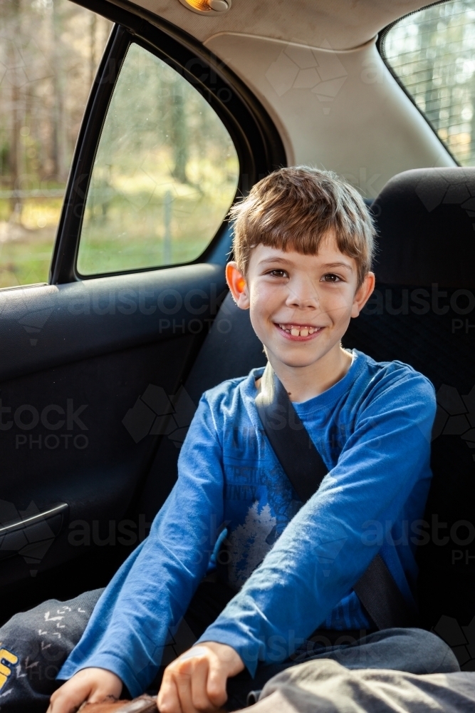 Happy young boy wearing seat belt in car - Australian Stock Image