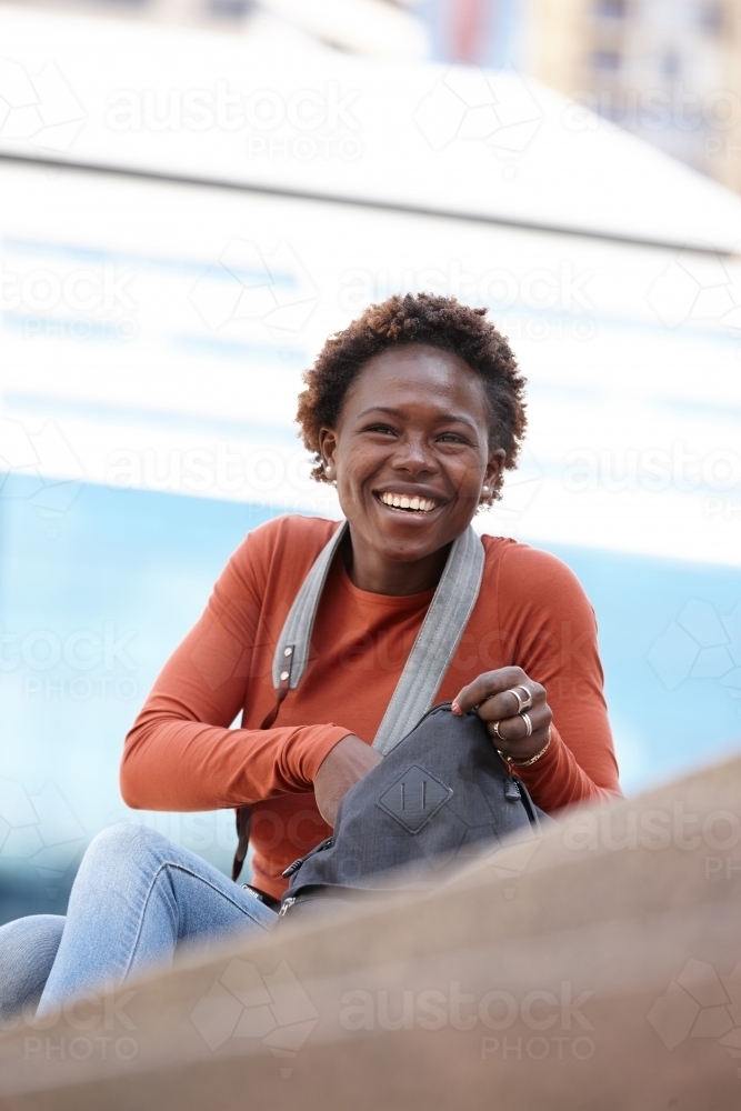 Happy young female photographer opening bag in city - Australian Stock Image